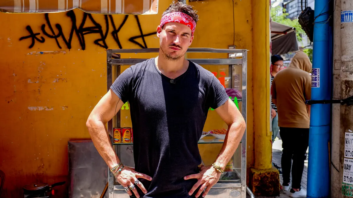 Fabian Zbinden mit rotem Stirnband vor einer gelben Hauswand an einem Strassenstand